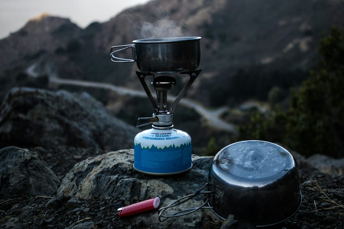 Compact camping gas stove with a pan on a cliff