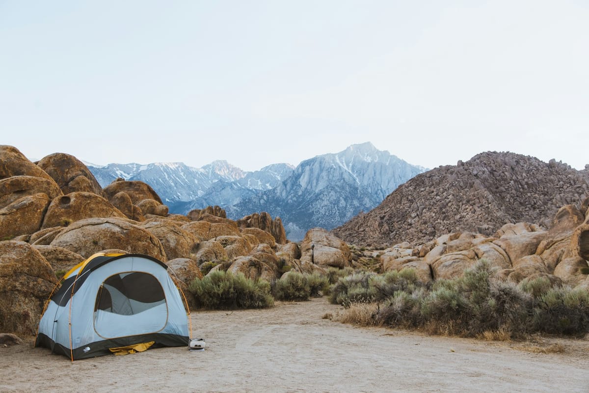Dome tent set up beside boulders overlooking mountains